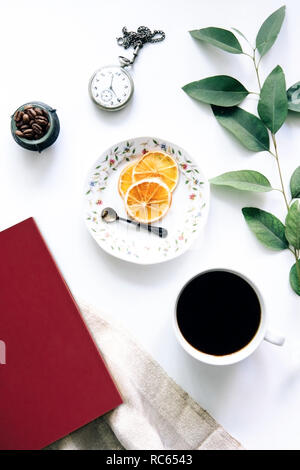 Coffee and red book on the table with dried oranges and old pocket watch - Peaceful ambience - Tea time - Work Ambience Stock Photo