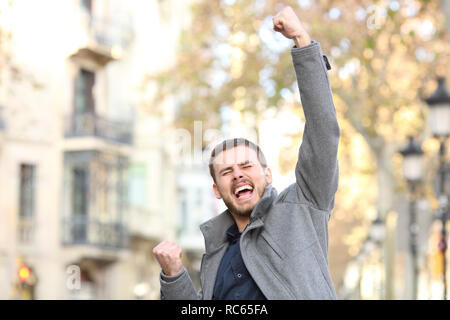 Portrait of an excited man raising arm in the street in winter Stock Photo