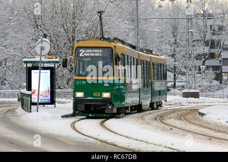 Helsinki, Finland - January 9, 2019: Green HSL tram No. 2 on a tram stop on a day of winter with snowfall in Helsinki. Stock Photo