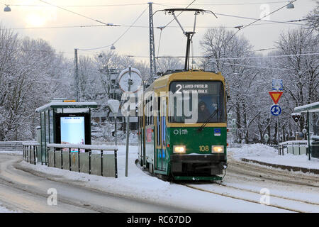 Helsinki, Finland - January 9, 2019: Green HSL tram No. 2 on a tram stop on a day of winter with light snowfall in Helsinki. Stock Photo