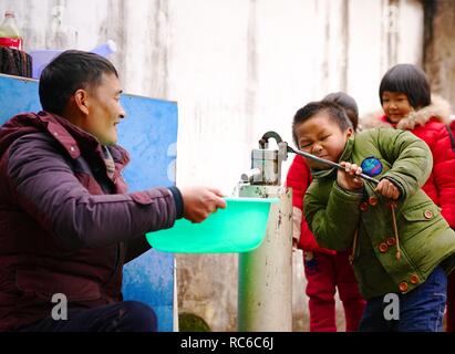 (190114) -- NANCHANG, Jan. 14, 2019 (Xinhua) -- A student helps principal Zhang Zhanliang pump water at Huangni elementary school in Chuntao Town of Yujiang District of Yingtan City, east China's Jiangxi Province, Jan. 3, 2019. Zhang Zhanliang, the principal of Huangni primary school, has been known nationwide recently for taking care of the school's left-behind children, whose parents are migrant workers in towns and cities. For years, there's no canteen at Huangni elementary school. Appointed as principal in 2018, Zhang Zhanliang spent his own money cooking additional meal for these left-beh Stock Photo