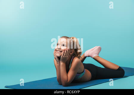 Cheerful little girl wearing sport clothes doing exercises with fitness  ball isolated over blue background Stock Photo - Alamy