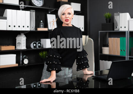 young girl stands near computer Desk in a stylish business office Stock Photo