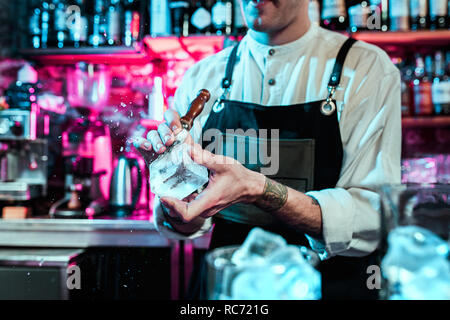 Expert barman is making cocktail at night club or bar. Glass of fiery cocktail on the bar counter against the background of bartenders hands with fire. Barman day concept Stock Photo