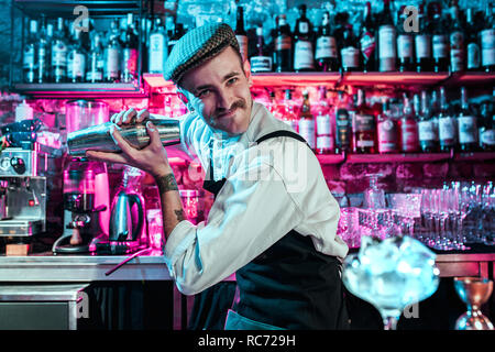 Expert barman is making cocktail at night club or bar. Glass of fiery cocktail on the bar counter against the background of bartenders hands with fire. Barman day concept Stock Photo