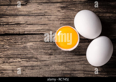 broken and whole chicken eggs on wooden background Stock Photo
