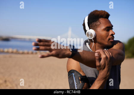 Purposeful African man stretching muscles of shoulder Stock Photo