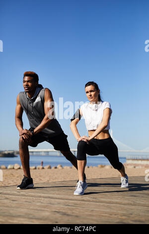 Interracial couple practicing warmup outdoors Stock Photo
