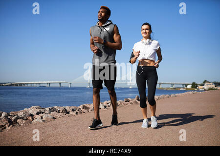 Multi-ethnic couple jogging on city beach Stock Photo