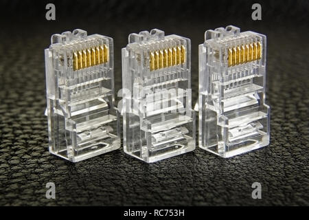 three RJ-45 connectors in a row close-up on dark background Stock Photo