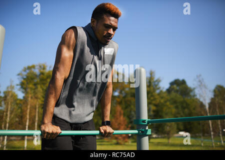 Doing dips at sports ground Stock Photo