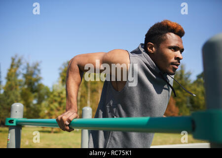 Motivated black man doing dips outdoors Stock Photo