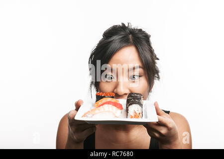 Beautiful young asian woman holding plate with sushi set isolated over white background Stock Photo