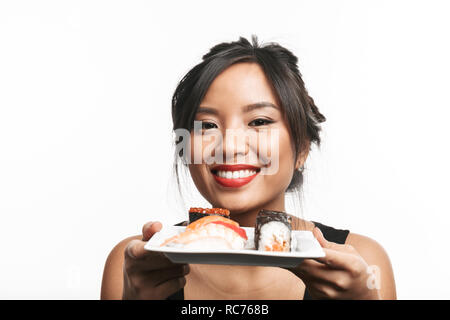 Beautiful young asian woman holding plate with sushi set isolated over white background Stock Photo