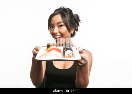 Beautiful young asian woman holding plate with sushi set isolated over white background Stock Photo