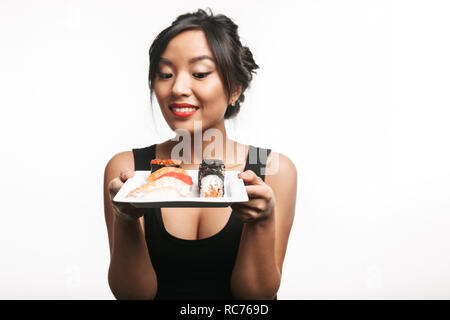 Beautiful young asian woman holding plate with sushi set isolated over white background Stock Photo