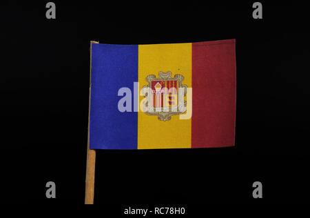 A official and national flag of the Principality of Andorra on toothpick on black background. A vertical tricolour of blue, yellow and red with the Na Stock Photo