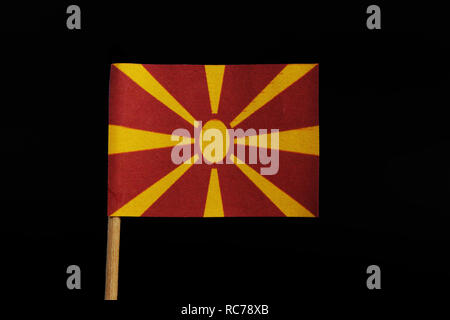 A unique and very original, national flag of the Republic of Macedonia on toothpick on black background. Stylised yellow sun on red field, with eight  Stock Photo