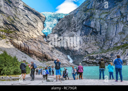 Norway, Olden - August 1, 2018: People at near lake and Briksdal or Briksdalsbreen glacier with melting blue ice, nature landmark Stock Photo