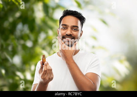 indian man applying natural grooming oil to beard Stock Photo