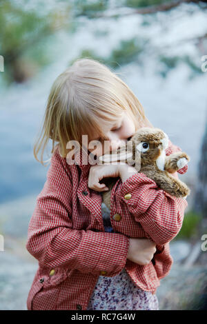 Girl kissing stuffed rabbit Stock Photo