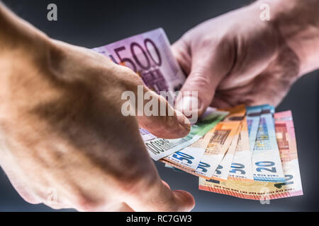 Male hands holding euro banknotes and the other hand to receive a bribe. Stock Photo