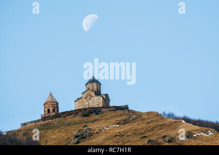 Caucasus mountains, ancient Gergeti Trinity church Tsminda Sameba against blue sky and supermoon, landmark of Georgia Stock Photo