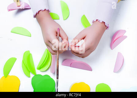 Child cuts an eggs for Easter out of paper. Sheets of colored paper. Kids art. Kids crafts. Crafts concept. How to make a greeting card Easter Stock Photo