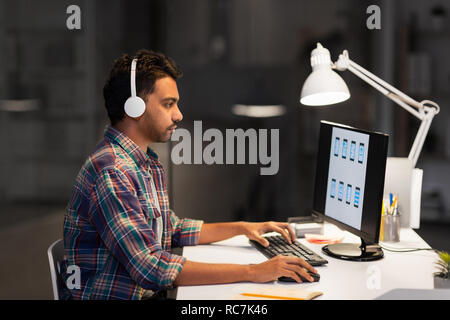 creative man in headphones working at night office Stock Photo
