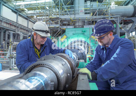 Engineers inspecting gears at generator end in nuclear power station during outage