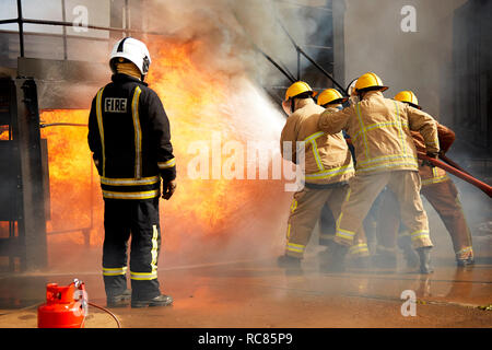 Rear view of male firefighter spraying water at fire station Stock ...