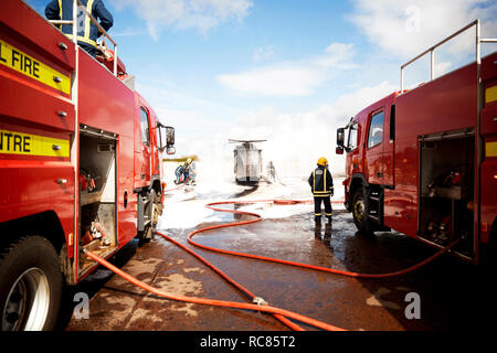 Firemen training, team of firemen spraying firefighting foam at mock helicopter at training facility Stock Photo