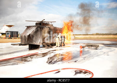 Firemen training, team of firemen spraying firefighting foam at mock helicopter fire at training facility Stock Photo