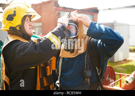 Firemen training, supervisor helping fireman with breathing apparatus at training facility Stock Photo