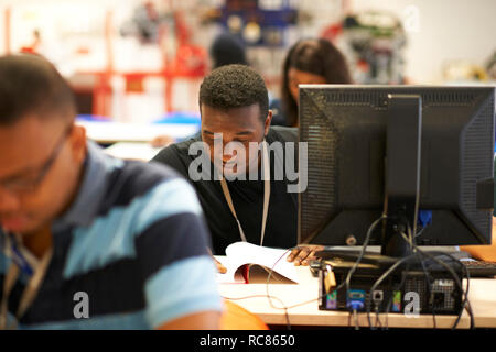 Male higher education students working at desks in college classroom Stock Photo