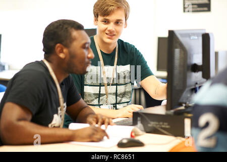 Male higher education students working at computer in college classroom Stock Photo