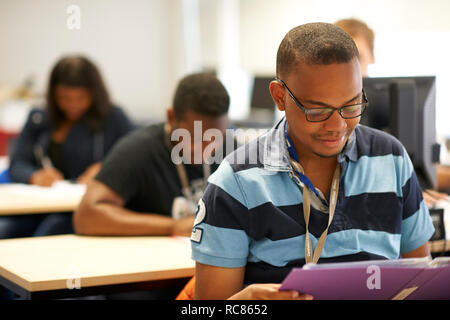 Male higher education student reading file in college classroom Stock Photo