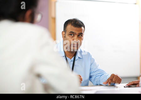 Lecturer talking to college students in classroom Stock Photo