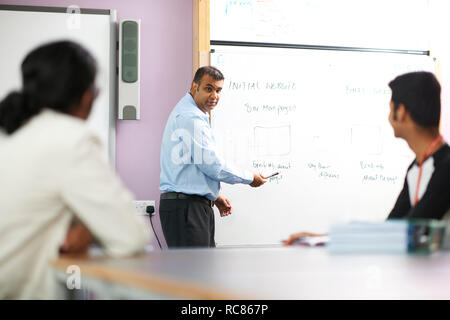 Lecturer talking to college students in classroom Stock Photo