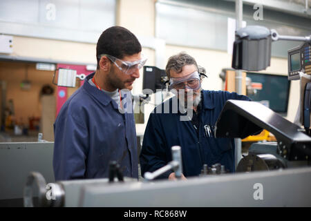 Lecturer teaching student to operate machine in workshop Stock Photo