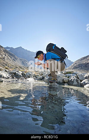 Hiker drinking from pool, Mont Cervin, Matterhorn, Valais, Switzerland Stock Photo