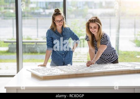 Colleagues brainstorming over architectural model Stock Photo