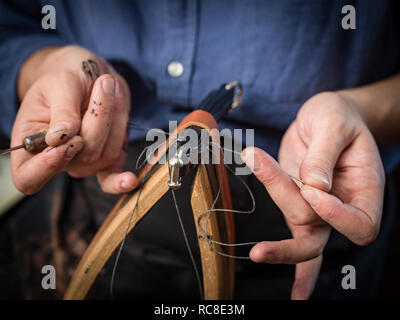 Leatherworker stitching handbag in workshop, close up of hands Stock Photo
