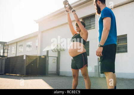 Pregnant woman and personal trainer working out outdoors Stock Photo