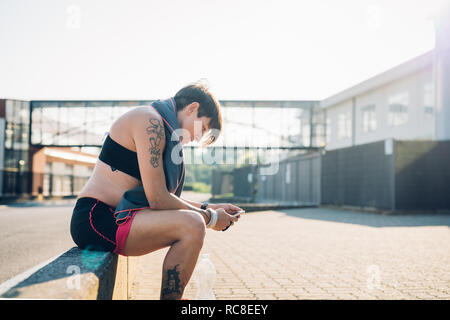 Pregnant woman reading text message at workout Stock Photo