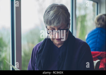 A senior woman is looking at the menu in a cafe Stock Photo
