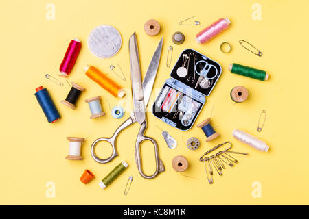 Composition with threads and sewing accessories - scissors, centimeter, pins on yellow background. Stock Photo