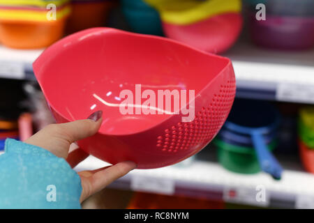 Plastic bucket for fruits in female hand on shop background Stock Photo