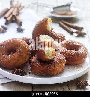 Homemade donuts with sugar and cinnamon on a wooden background. Rustic style, selective focus. Stock Photo