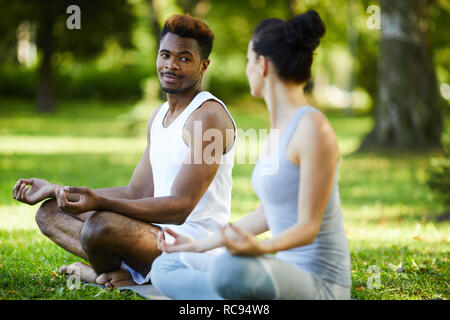 Content interracial couple talking during outdoor yoga practice Stock Photo